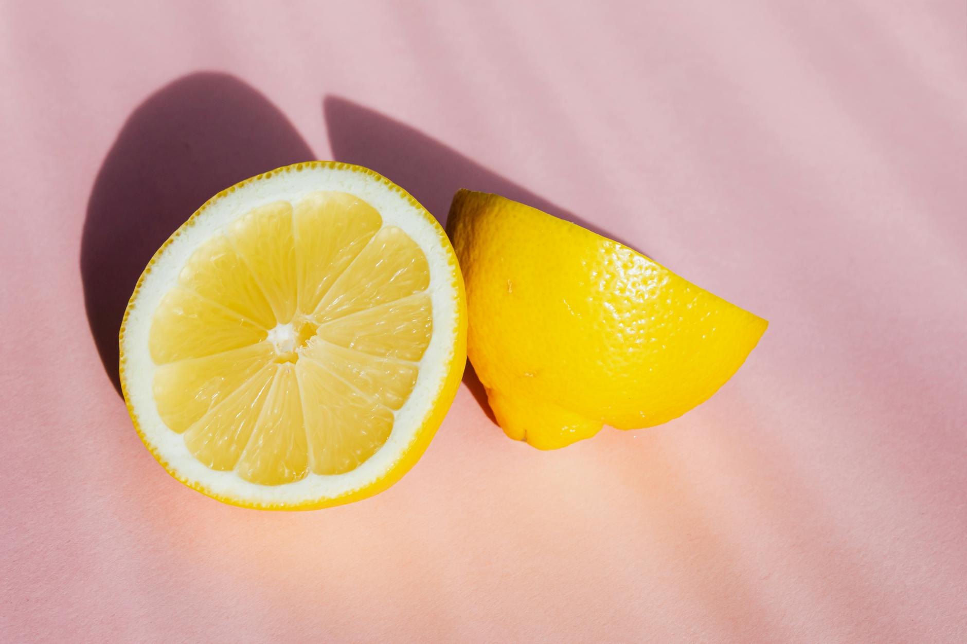 Fresh lemon halves on a pink background, symbolizing clarity and brightness in relationships
