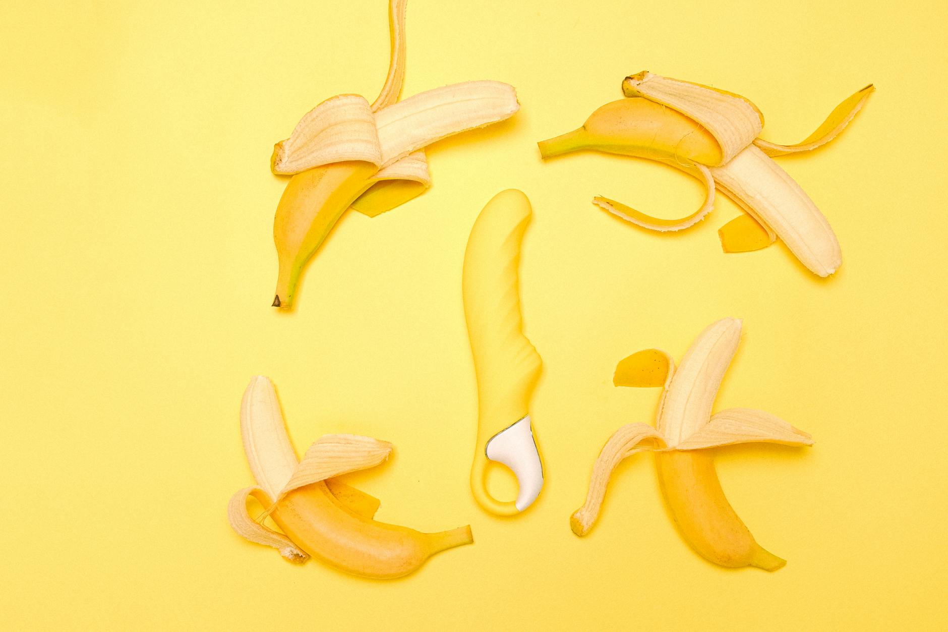 Vibrador de limão amarelo em composição criativa com bananas em fundo amarelo pastel