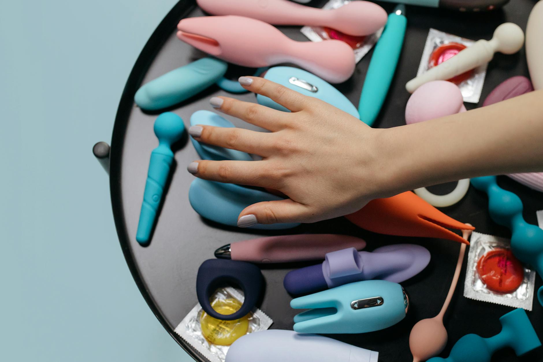 Hand holding a sleek orange vibrator against a minimalist backdrop, ready for pleasure exploration