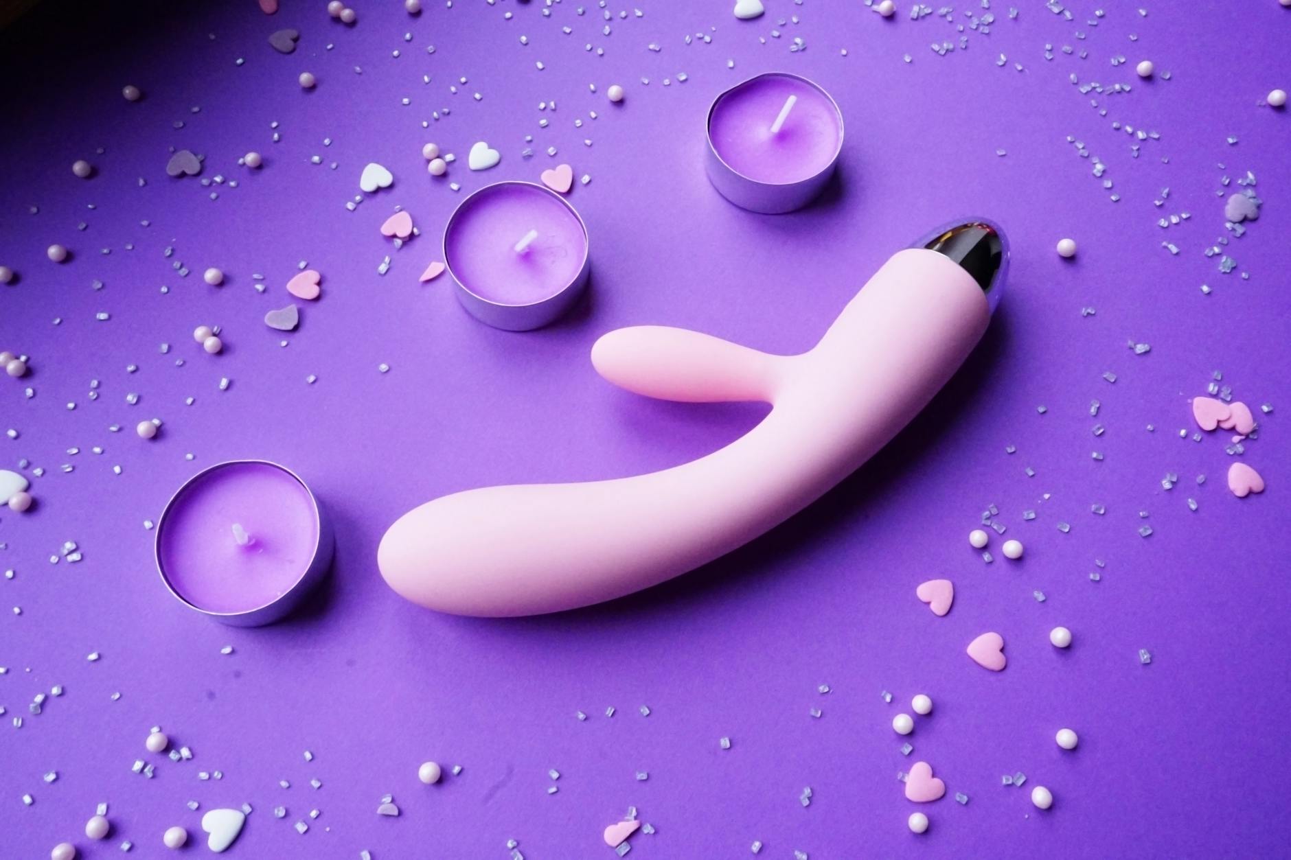 Colorful vibrators and flowers on a bright yellow background, representing a welcoming introduction to intimate exploration